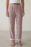 Pantalon pyjama femme mauve en pilou côtelé, taille élastiquée et ourlet à pompons blancs, vue de face